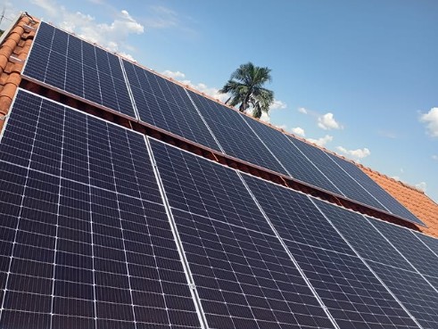 Painéis solares em telhado residencial com coqueiro ao fundo